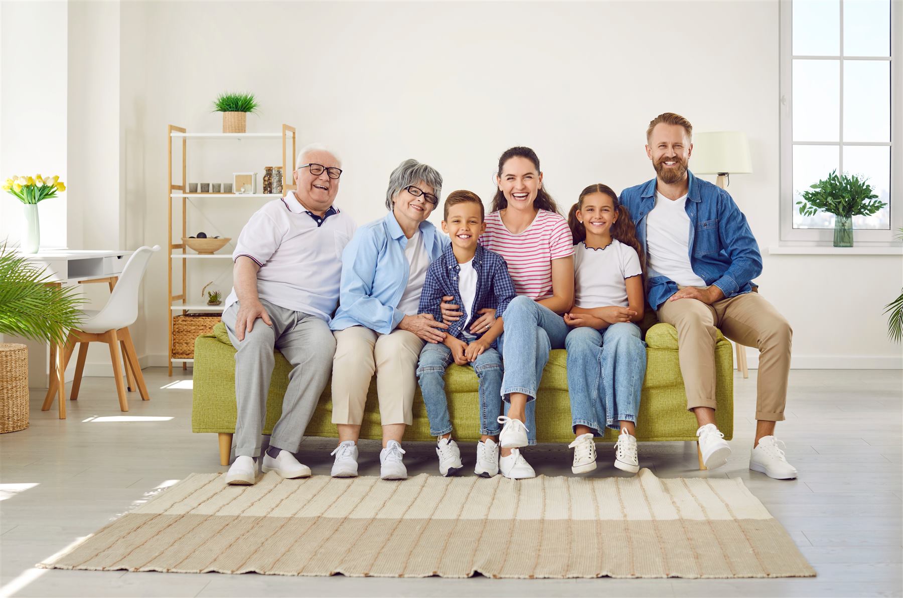 Tre generazioni della stessa famiglia sorridono sedute insieme sul divano