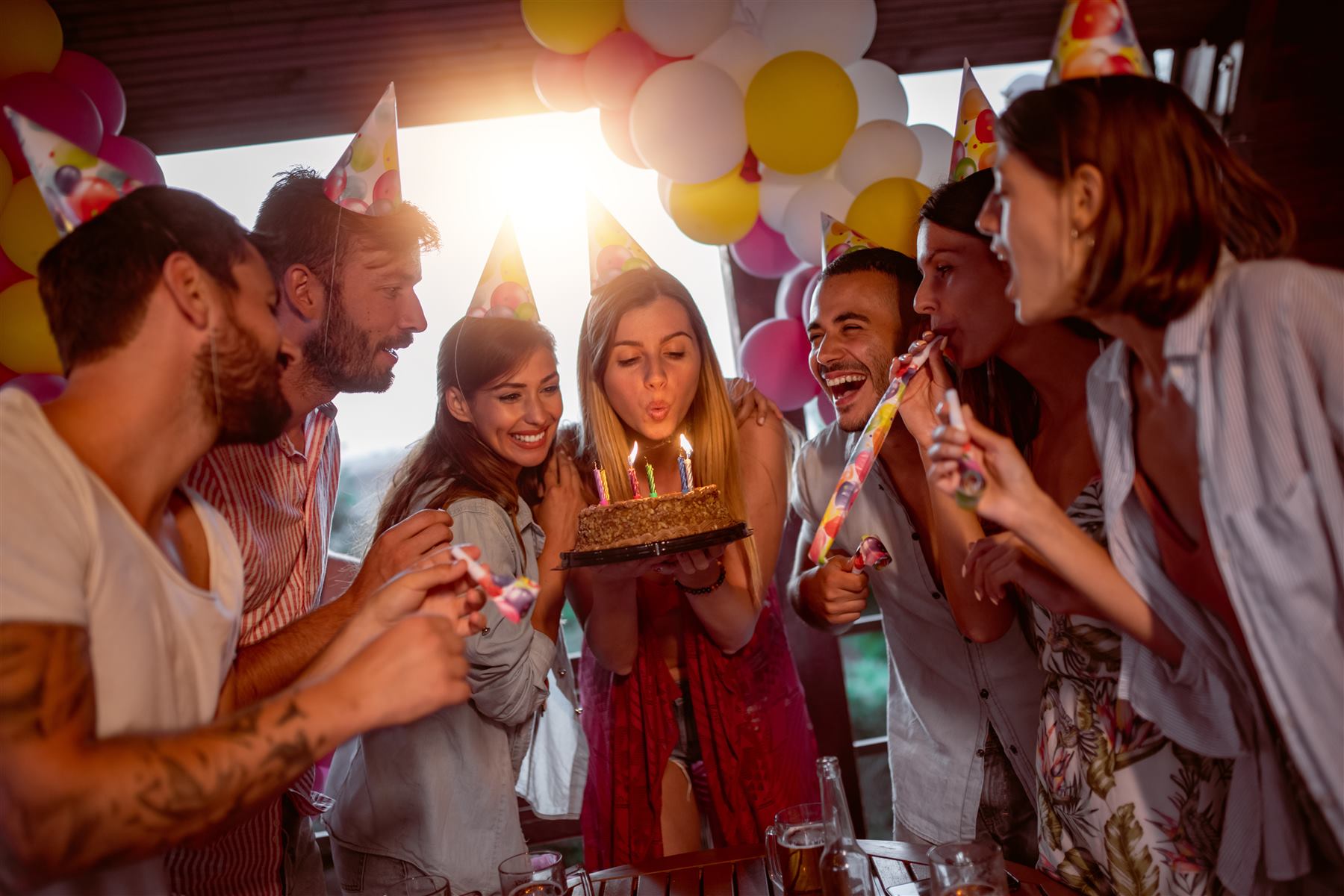 Un gruppo di amici festeggia un compleanno con una torta e candeline