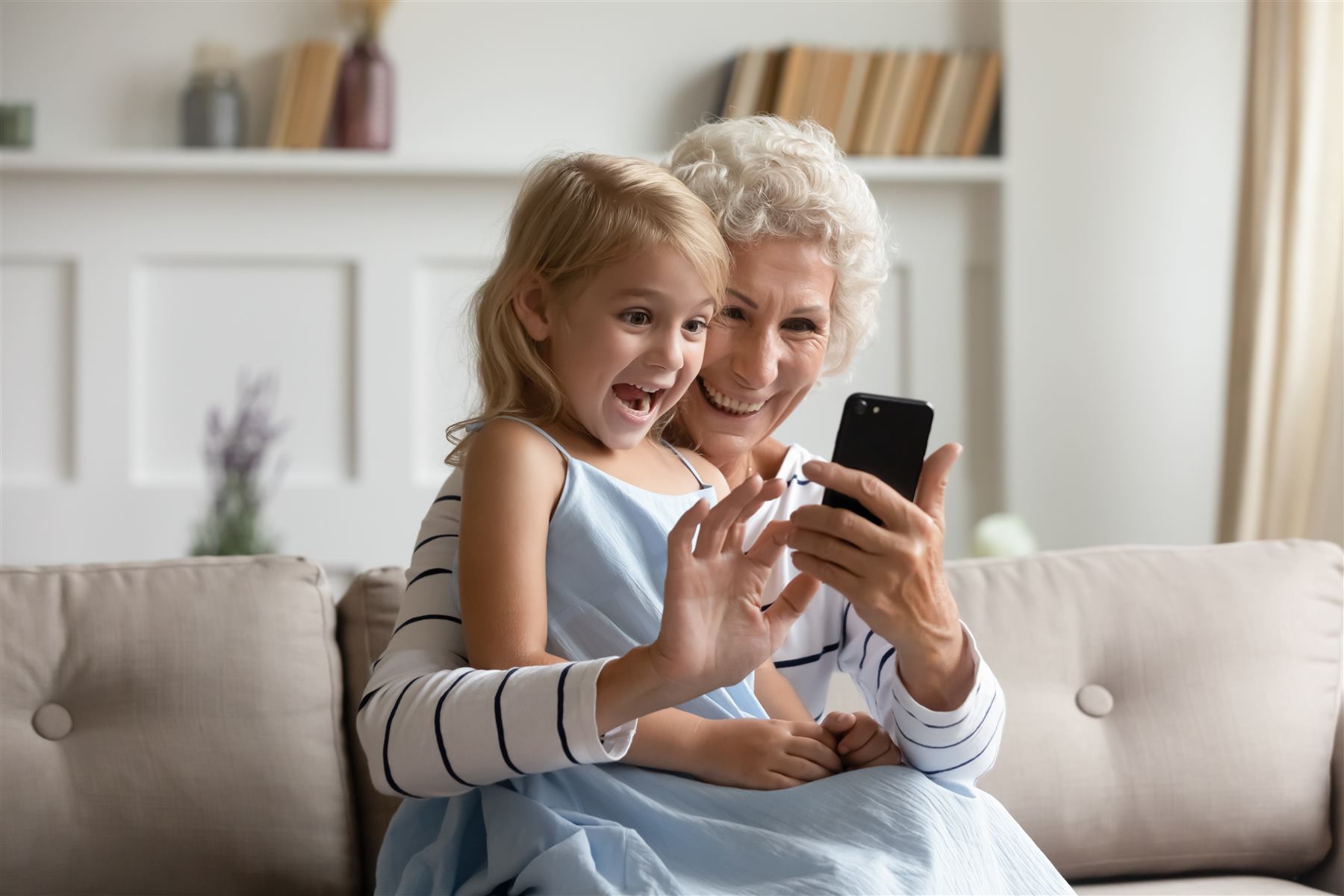 Una nonna e sua nipote ridono guardando insieme un messaggio sul telefono