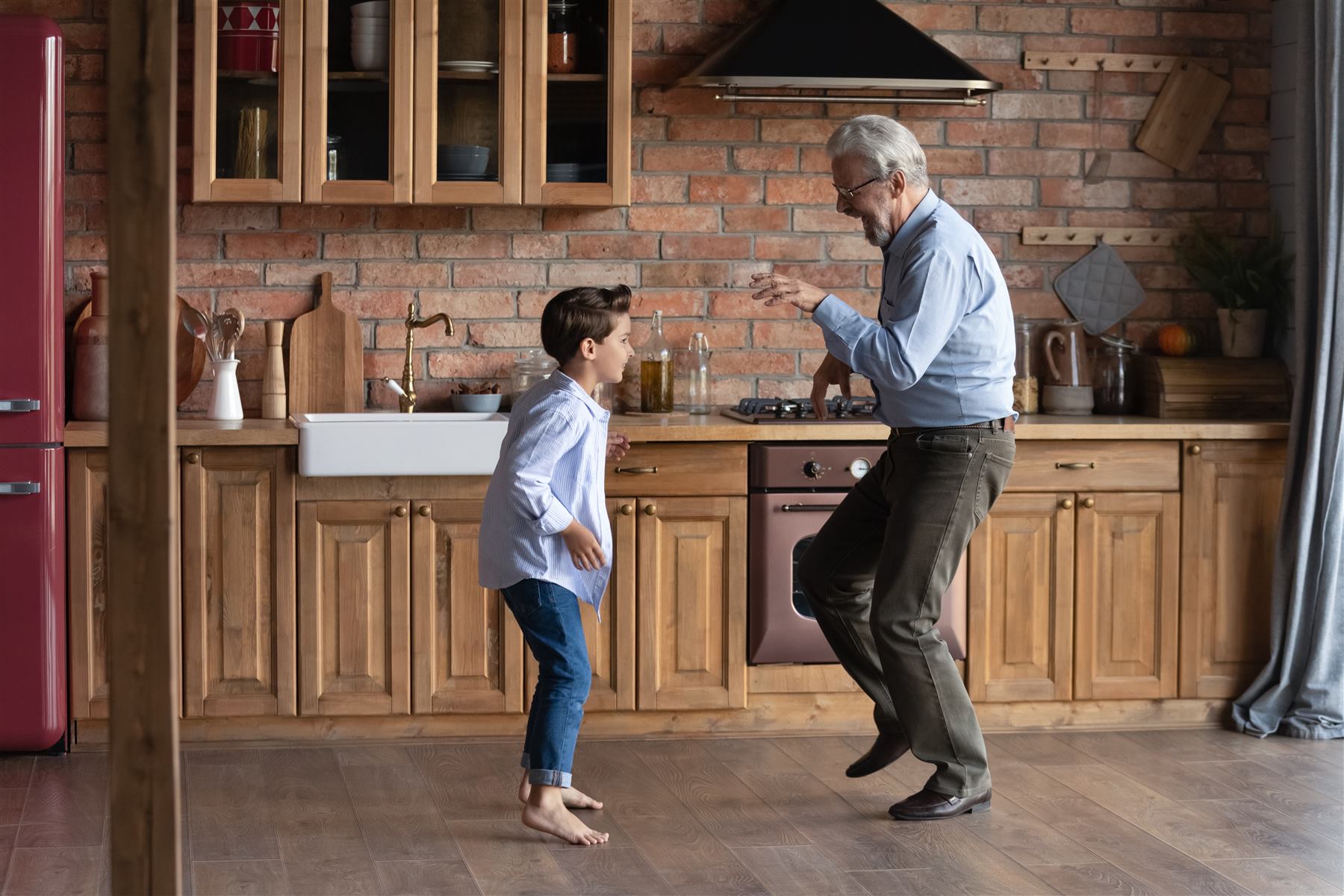 Un nonno balla con il nipote in cucina, entrambi ridono
