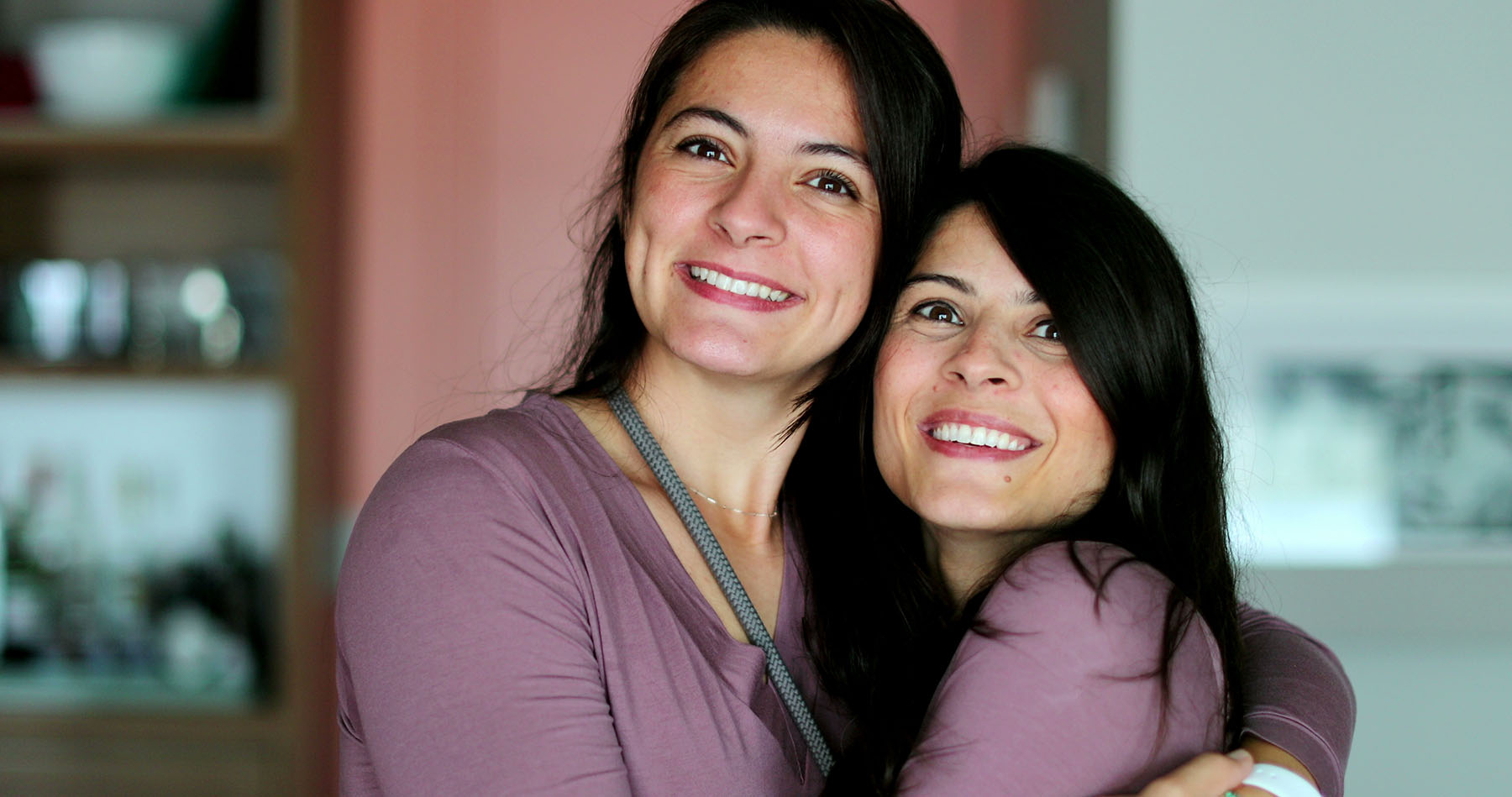 Due sorelle adulte sorridono insieme, vicine