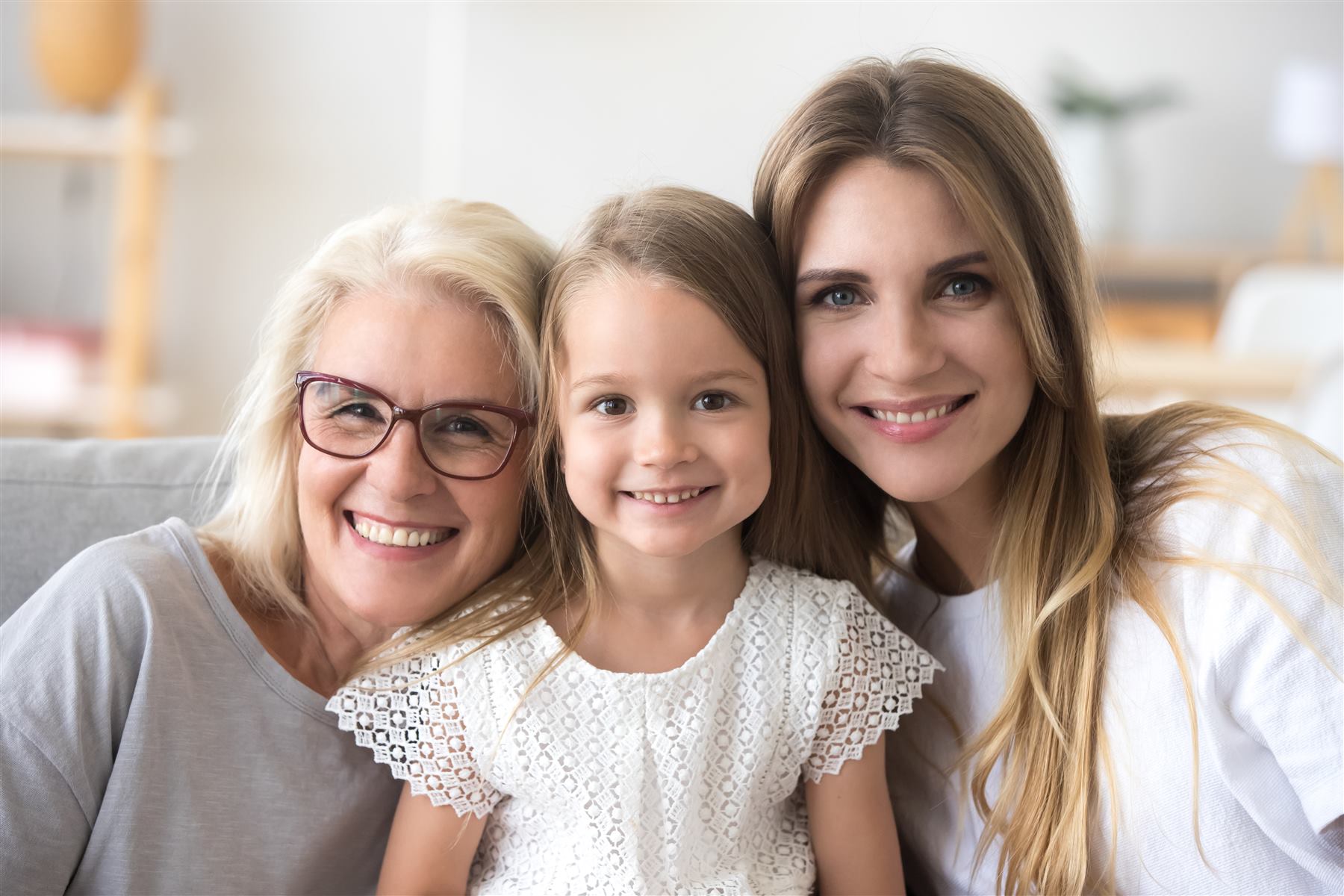 Nonna, mamma e figlia sorridono insieme, guance vicine